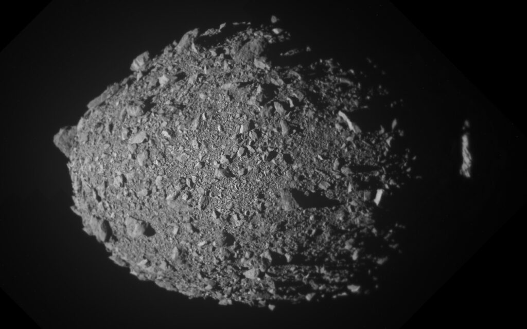 Close-up of the boulder-strewn asteroid Dimorphos, built from DART spacecraft final images, with the edge of Didymos at right