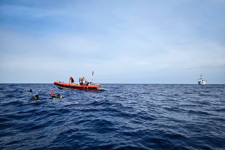 Divers surface with a bright buoy near NOAA Ship Nancy Foster